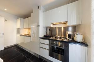 a kitchen with white cabinets and a stove at Elégant appartement proche bord de mer in Beaulieu-sur-Mer