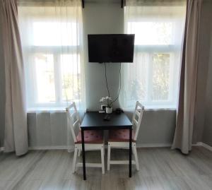 una sala da pranzo con tavolo, due sedie e televisore di Mezrozes a Ventspils