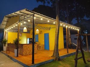 una casa amarilla con luces en una cubierta por la noche en Wildbird Hotel en Tràm Chim