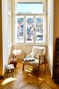 Zimmer mit einem Stuhl und einem großen Fenster in der Unterkunft Altbau-Traum im Stadtzentrum in Graz