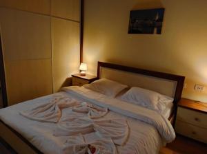 Schlafzimmer mit einem Bett mit weißer Bettwäsche und Kissen in der Unterkunft Perfect Attic in Tirana