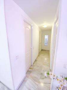 a hallway with white walls and white floors and a mirror at Los Girasoles in Marina Botafoch in Ibiza Town