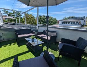 eine Terrasse mit Stühlen, Tischen und einem Sonnenschirm in der Unterkunft Leipzig Residenz Goethe Apartment mit 2 Dachterrassen in Leipzig