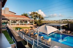 une piscine avec des chaises et un bâtiment dans l'établissement Hotel Village Premium Caruaru, à Caruaru