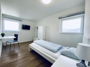1 Schlafzimmer mit einem Bett, einem Schreibtisch und 2 Fenstern in der Unterkunft Monteurzimmer ZIMMERzuVERMIETEN in Deitingen Industriestrasse in Deitingen
