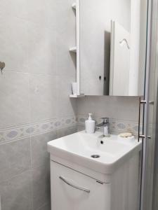 Baño blanco con lavabo y espejo en Studio Petlja - Igalo, en Herceg-Novi