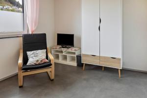Habitación con silla, TV y escritorio. en Apfelkiste, en Meßstetten