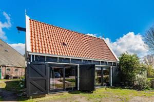 een grote zwarte garage met een rood dak bij Luxury private farmhouse cottage near Amsterdam plus home cinema in Ilpendam