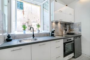 a kitchen with white cabinets and a sink and a window at Passaggio studio in Corfu Town