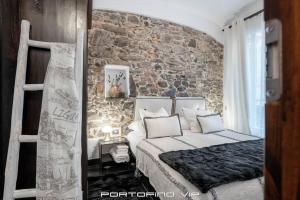 sypialnia z łóżkiem i ceglaną ścianą w obiekcie Portofino Luxury Front Marina by PortofinoVip w Protofino