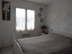 een slaapkamer met een wit bed en een raam bij Maison Grues, 3 pièces, 5 personnes - FR-1-476-31 in Grues