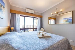 a bedroom with a blue bed with a mirror and a balcony at Clube Praia Mar Flat T1 in Portimão