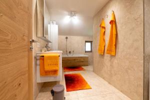 bagno con vasca e lavandino con asciugamani arancioni di Ferien am Sonnberg a Unken