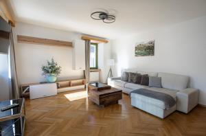 a living room with a white couch and wooden floors at Casa Bernina in Poschiavo