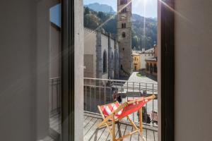 a chair on a balcony with a view of a city at Casa Bernina in Poschiavo
