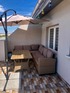 eine Terrasse mit einem Sofa, einem Tisch und einem Sonnenschirm in der Unterkunft Julia's Residence in Cisnădie