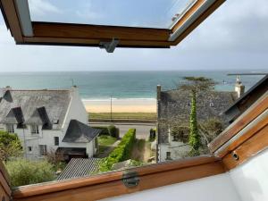 uma vista a partir de uma janela de uma casa e do oceano em Appartement la Sirène Audierne- Face à la plage de Trescadec em Audierne