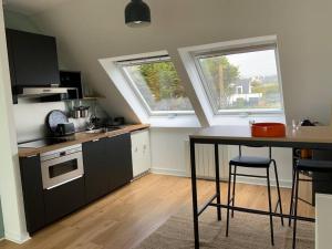 uma pequena cozinha com uma mesa e duas janelas em Appartement la Sirène Audierne- Face à la plage de Trescadec em Audierne
