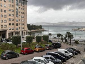 un grupo de autos estacionados en un estacionamiento cerca del océano en Piso en Vigo con vistas a la ría en Vigo