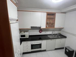 a kitchen with white cabinets and a sink at Piso en Vigo con vistas a la ría in Vigo
