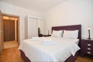 een slaapkamer met een groot bed en handdoeken bij Apartman Ana in Herceg-Novi