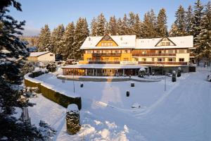 un grand bâtiment dans la neige avec des arbres enneigés dans l'établissement Hotel SLUNEČNÁ LOUKA, à Lipno nad Vltavou