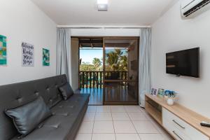 sala de estar con sofá y TV de pantalla plana en Nannai Residence by AFT, en Porto de Galinhas