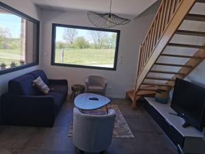 a living room with a couch and a tv and stairs at La Maison du Colombier in Le Fied