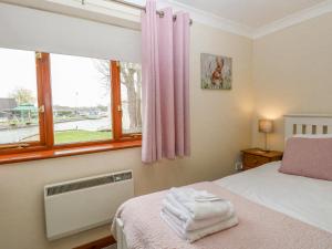 a bedroom with a bed with pink curtains and a window at Solace Lodge in Norwich