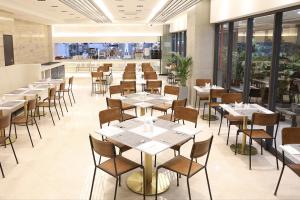un restaurante con mesas y sillas blancas y ventanas en Kynd Hotel en Seongnam