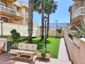 un banco de parque en un patio con palmeras en Apartamento playero con vistas a la montaña, en Castell de Ferro