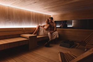 a man and a woman sitting in a sauna at Glass Resort in Rovaniemi