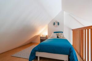- une chambre mansardée avec un lit bleu dans l'établissement Bananec- Appt à 300 mètres de la plage, à La Forêt-Fouesnant