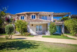 una casa con ventanas azules y patio en Villas Resort Wellness & SPA, en Castiadas