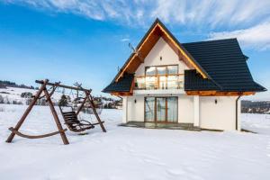 een huis in de sneeuw met een schommel bij Tatra Apartments z zewnętrznym jacuzzi in Biały Dunajec