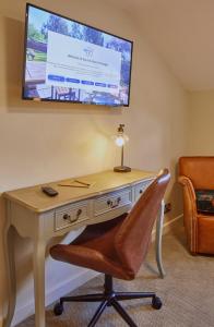 a desk with a chair and a television on a wall at Full Moon Inn Rudge in Frome