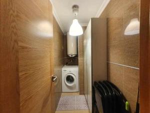 a small bathroom with a washing machine and a door at Apartamento Playa Jardín in Ribeira