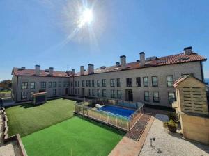 a large building with a swimming pool in the yard at Apartamento Playa Jardín in Ribeira