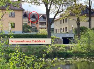 a red sign in front of a house next to a river at Ferienwohnung Teichblick -Balkon- in Dresden