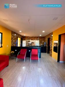 a lobby with two red chairs and a bar at Pousada Águas de Peroba Flats e Suites in Maragogi