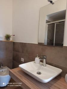ein Badezimmer mit einem weißen Waschbecken und einem Spiegel in der Unterkunft Il Maestrale in Isola Rossa