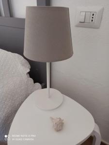 una lampada bianca seduta su un tavolo accanto a un letto di Il Maestrale a Isola Rossa