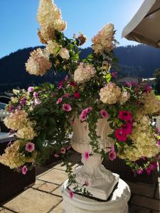 un jarrón blanco lleno de flores en un balcón en Hotel Garni Zimmermann en Reith bei Kitzbühel