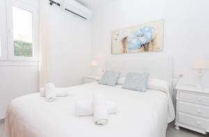 a white bedroom with a white bed and a window at Villa Albe by Sonne Villas in Cala Galdana