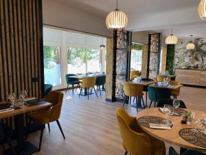 a restaurant with wooden tables and chairs and windows at Urban Style Cannes Mouans-Sartoux - Piscine Extérieure - Parking Gratuit in Mouans-Sartoux