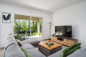 sala de estar con sofá y TV de pantalla plana en Seyssuel • Villa Paisible • HostisY en Seyssuel