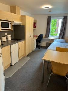a room with a bed and a table and a kitchen at Cosy Studios at New Hall located in the heart of Nottingham in Nottingham