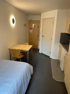 Zimmer mit einem Bett, einem Schreibtisch und einem Tisch in der Unterkunft Cosy Studios at New Hall located in the heart of Nottingham in Nottingham