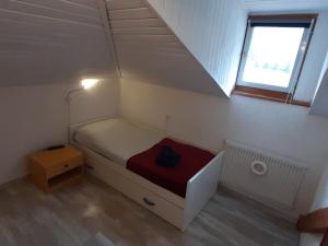 un piccolo letto in una piccola stanza con finestra di Ampia Mansarda a Dimaro in Val di Sole a Monclassico