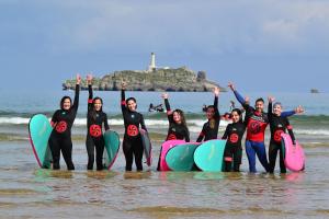 a group of people standing on the beach with surfboards at Hotel Pinar Somo Surf in Somo